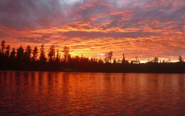 an orange and purple sky is reflected in water